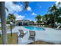 Community pool area featuring ample seating, swaying palm trees, and clear blue water, perfect for relaxation at 13416 Greenpointe Dr, Orlando, FL 32824