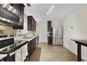 Well-equipped kitchen featuring stainless steel appliances, dark wood cabinets, and sleek laminate flooring at 14620 Old Forest Ct, Orlando, FL 32826
