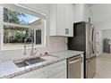Close-up of a kitchen sink and granite countertops complimented by stainless steel appliances and white cabinets at 1475 James St, New Smyrna Beach, FL 32168