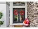 Elegant front door with decorative wreaths, stone accents, and a welcoming seating area at 243 Sagecrest Dr, Ocoee, FL 34761