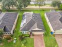 Aerial view of a house with solar panels, a brick driveway, and lush greenery surrounding the property at 254 Andalusia Loop, Davenport, FL 33837