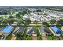 Wide aerial shot of a neighborhood with lush landscaping, a community pond, and a mix of single-Gathering homes at 254 Andalusia Loop, Davenport, FL 33837