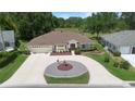 An aerial view of a lovely home showcasing a circular driveway with fountain and lush green landscaping at 26901 Racquet Cir, Leesburg, FL 34748