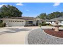 Inviting home featuring a circular driveway, lush landscaping, and an attached two-car garage at 26901 Racquet Cir, Leesburg, FL 34748