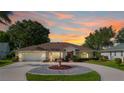 Charming single-story home with circular driveway, fountain, mature trees, and attached two-car garage at 26901 Racquet Cir, Leesburg, FL 34748