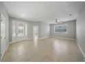 Spacious living room featuring tile floors, a ceiling fan, and ample natural light from large windows at 5829 Valentino Way, Lakeland, FL 33812