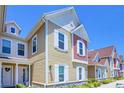 Two-story townhome showcasing light yellow siding, white trim, and neatly landscaped grounds at 7595 Sunny Dreams Ln, Kissimmee, FL 34747