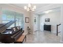 Elegant foyer with neutral tile flooring, a grand piano, and a staircase leading to the upper level at 8643 Coventry Park Way, Windermere, FL 34786