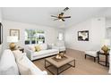 Bright living room features wood floors, large window, ceiling fan, and neutral decor at 25929 Newcombe Cir, Leesburg, FL 34748