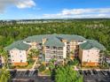 Aerial view showcasing the condo building, lush landscaping, and ample parking at 9051 Treasure Trove Ln # 405, Kissimmee, FL 34747