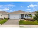 Attractive single-story home featuring a brick-paved driveway, lush landscaping, and light blue siding at 6137 Blue Pond Way, St Cloud, FL 34771