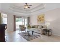 Bright living room with tray ceiling, neutral walls, tile flooring, and sliding glass door to patio at 972 Bighorn St, Oviedo, FL 32765