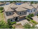 An aerial view showcases this two-story home with a tile roof, brick driveway, and well-manicured landscaping at 1491 Rolling Fairway Dr, Davenport, FL 33896