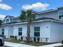 View of well-manicured lawn and white two-story townhomes, each with a palm tree in the front at 2025 Claudia Ln # 2025, Kissimmee, FL 34741