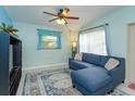 Inviting living room showcasing tile flooring, a blue sectional sofa, and a ceiling fan at 411 Hibiscus Rd, Casselberry, FL 32707