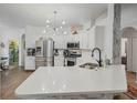Bright, open kitchen with stainless steel appliances, white cabinetry and a large center island at 506 Pineloch Dr, Haines City, FL 33844