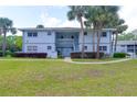 Inviting two-story condo with lush green lawn, mature landscaping, and an open staircase leading to upper units at 576 Fairways Ln # M103, Ocala, FL 34472