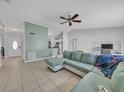 Open-concept living room featuring tile flooring, a ceiling fan, and a comfortable blue sectional sofa at 62 York Ct, Kissimmee, FL 34758