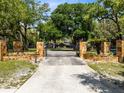 View of stone column gated entrance to property with mature trees and a long driveway at 840 Dyson Dr, Winter Springs, FL 32708
