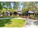 Stunning exterior of log cabin style home with stone details, mature trees, and a welcoming front yard at 840 Dyson Dr, Winter Springs, FL 32708