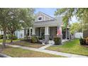 Charming gray single-Gathering home featuring a covered front porch, manicured landscaping and an American flag at 14131 Paradise Tree Dr, Orlando, FL 32828