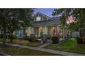 Charming gray single-Gathering home at dusk featuring a covered front porch, manicured landscaping and an American flag at 14131 Paradise Tree Dr, Orlando, FL 32828