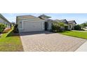 Beautiful single-story home with a well-manicured lawn and a spacious paver driveway leading to a two-car garage at 1925 Estuary Ln, Kissimmee, FL 34747