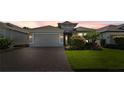 Inviting single-story home featuring a well-kept lawn and a convenient two-car garage with paver driveway at 1925 Estuary Ln, Kissimmee, FL 34747