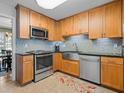 Well-lit kitchen features wooden cabinets, stainless steel appliances, mosaic backsplash, and a stainless farmhouse sink at 210 Lonesome Pine Dr, Longwood, FL 32779