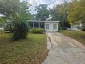 A single-story home with a screened-in porch and a concrete driveway surrounded by mature trees at 2507 Lafayette Ave, Winter Park, FL 32789