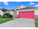 Charming single-Gathering home showcasing a well-manicured lawn and inviting red garage door at 2535 Oneida Loop, Kissimmee, FL 34747