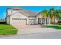 Inviting single-Gathering home features a manicured lawn, brick driveway, and three-car garage at 3041 Cardillino Way, Kissimmee, FL 34741
