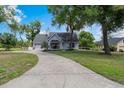 A well-maintained single-Gathering home with a long driveway and lush green lawn surrounded by mature trees at 30746 Fairview Ave, Tavares, FL 32778