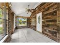 Bright sunroom featuring wood accent wall, brick siding, tile flooring, and outdoor access at 3137 East St, Oviedo, FL 32765