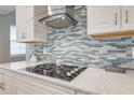Close-up of modern kitchen features custom backsplash and sleek cooktop at 6667 Alder Rd, Harmony, FL 34773