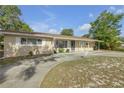 A tan single-story home features a large driveway, covered parking, and tidy landscaping at 825 Second St, Orange City, FL 32763