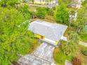 Aerial view of a quaint yellow home nestled among lush trees with a long driveway at 110 Riverside Ter, Edgewater, FL 32141