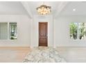 Elegant foyer with a decorative wood door, marble floors, and modern light fixture at 702 S Lake Adair Blvd, Orlando, FL 32804