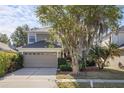 Well-maintained two-story home with mature trees, a two-car garage, and a tidy front yard at 9244 Pecky Cypress Way, Orlando, FL 32836