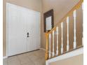Inviting foyer with a white front door, a staircase with wooden banisters, and tile flooring at 9244 Pecky Cypress Way, Orlando, FL 32836