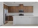 Modern kitchen featuring stainless steel appliances, a center island, and brown cabinets at 1026 Vineyard Ridge Rd, Minneola, FL 34715