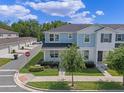 Beautiful two-story townhome with blue accents, a manicured lawn, and an inviting front porch seating area at 1324 Painted Bunting Ave, Oakland, FL 34787