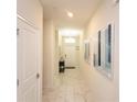 Hallway with white marble floors and white walls with modern art leading to the front door at 1577 Mulligan Blvd, Davenport, FL 33896