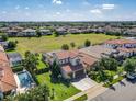 Expansive aerial view of a community with manicured lawns, red tile roofs, and a sparkling pool at 16675 Otterchase Ln, Winter Garden, FL 34787