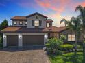 Beautiful two-story home with a red tile roof, brick driveway, three-car garage, and lush tropical landscaping at 16675 Otterchase Ln, Winter Garden, FL 34787