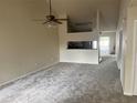 Spacious living room with neutral carpet, a ceiling fan, and a decorative wall cutout to the kitchen at 3530 Forest Branch Dr # F, Port Orange, FL 32129