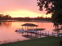 Picturesque sunset over a serene lake, featuring a charming dock with a covered gazebo at 4 Island Dr, Lake Mary, FL 32746