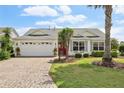 Charming single-story home with a well-manicured lawn, brick driveway, and a pop of color from the red front door at 433 Arcadia Lakes Dr, The Villages, FL 32162