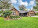 Beautiful brick home with a large window, flowering bushes, and a well-kept lawn, complemented by mature trees at 445 Songbird Way, Apopka, FL 32712