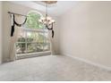 Bright living room with large windows, chandelier, tile flooring, and stylish curtains at 612 Stonefield Loop, Lake Mary, FL 32746